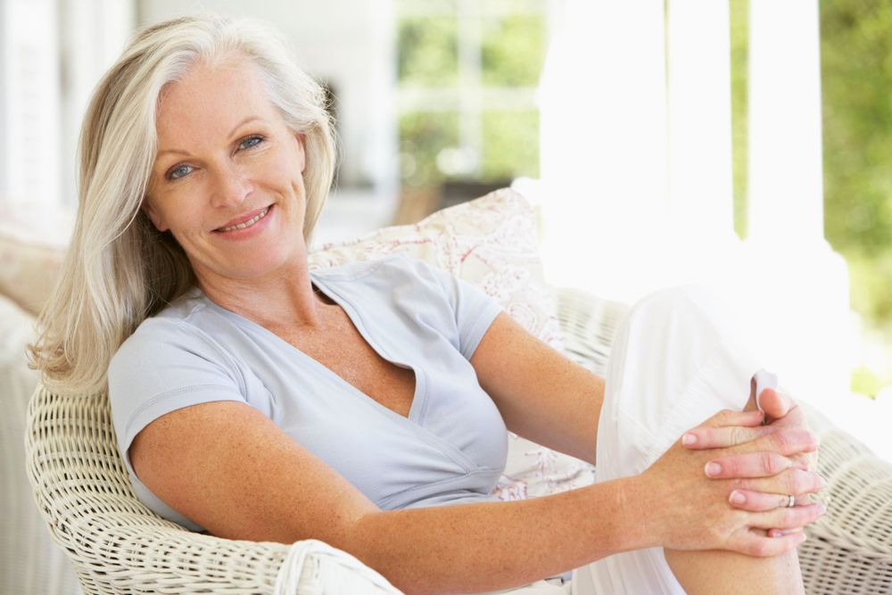 Happy, healthy middle aged woman sitting in wicker chair outside enjoying a beautiful day.