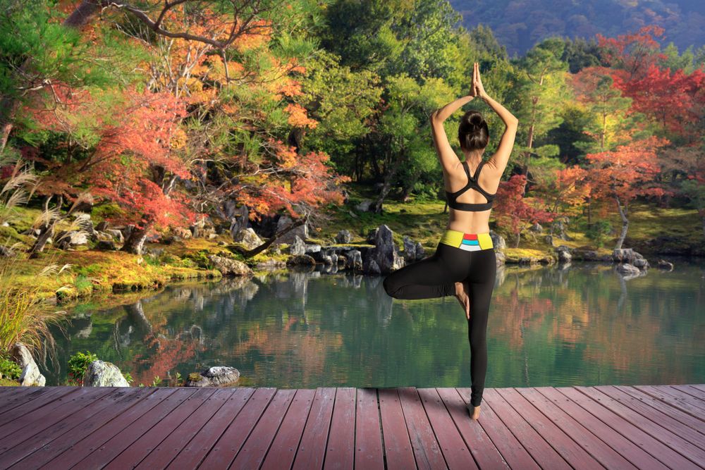 Young woman training yoga outdoor in autumn or fall park.